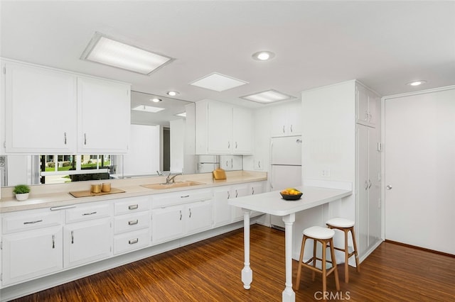 kitchen with white cabinets, freestanding refrigerator, and a sink