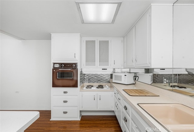 kitchen featuring white appliances, light countertops, white cabinets, dark wood-type flooring, and backsplash