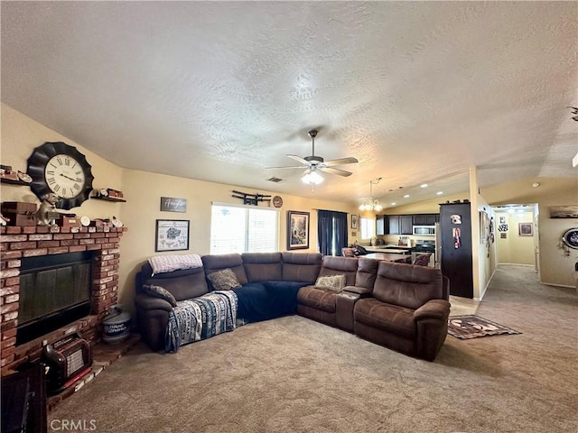 living room featuring a ceiling fan, a fireplace, vaulted ceiling, a textured ceiling, and light colored carpet