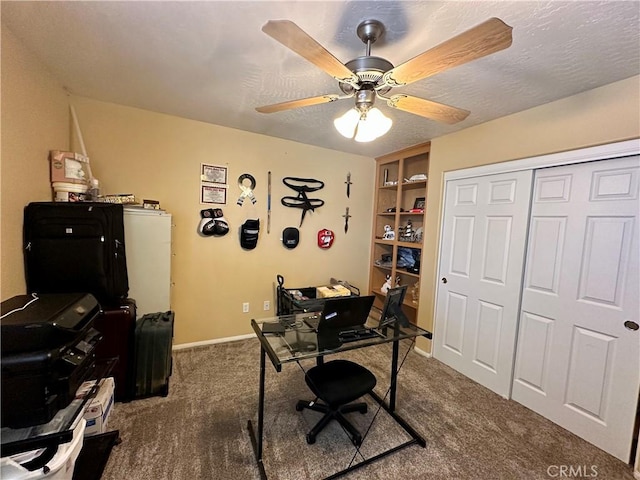 carpeted office space featuring a ceiling fan, baseboards, and a textured ceiling