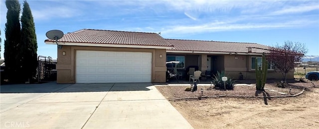 ranch-style home featuring concrete driveway, an attached garage, a tile roof, and stucco siding