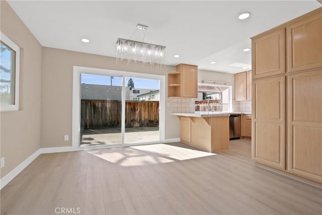 kitchen with tasteful backsplash, a healthy amount of sunlight, dishwasher, and a breakfast bar