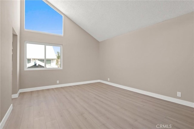 empty room featuring light wood finished floors, a textured ceiling, and baseboards