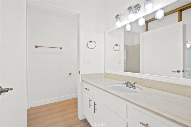 bathroom with baseboards, wood finished floors, and vanity