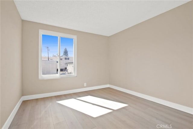 unfurnished room with wood finished floors, baseboards, and a textured ceiling