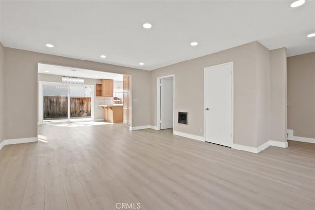 unfurnished living room featuring recessed lighting, baseboards, and light wood-style floors