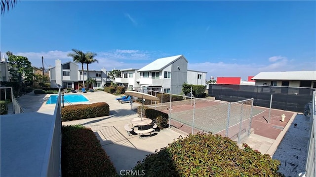 pool with a tennis court, fence, a residential view, and a patio