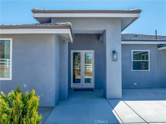 property entrance with a patio, french doors, and stucco siding