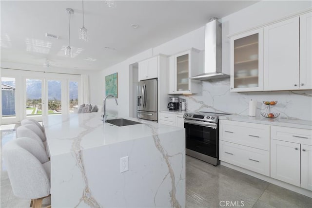 kitchen with visible vents, a sink, appliances with stainless steel finishes, wall chimney range hood, and backsplash