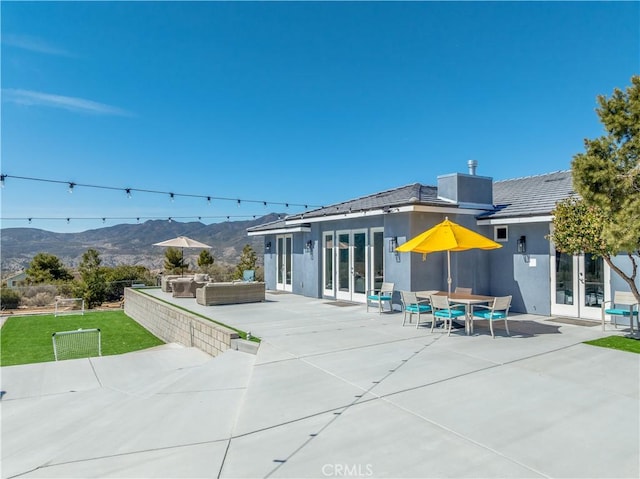 back of property featuring a patio, french doors, a mountain view, and stucco siding