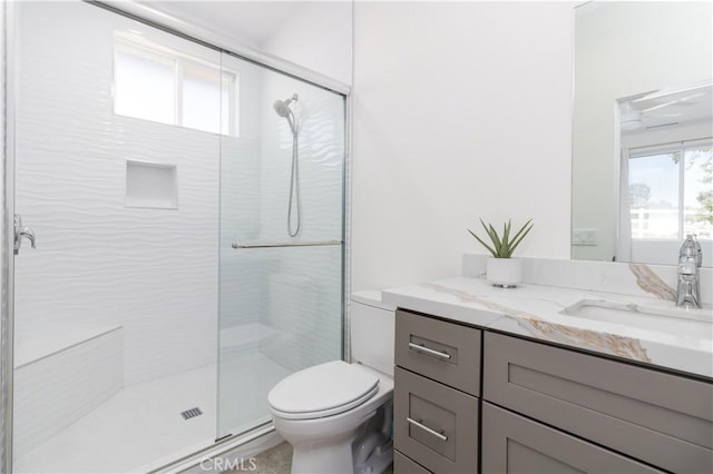 bathroom with toilet, a stall shower, and vanity