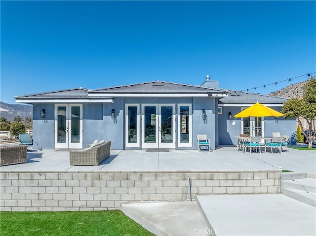 back of property with a tiled roof, french doors, a patio, and stucco siding