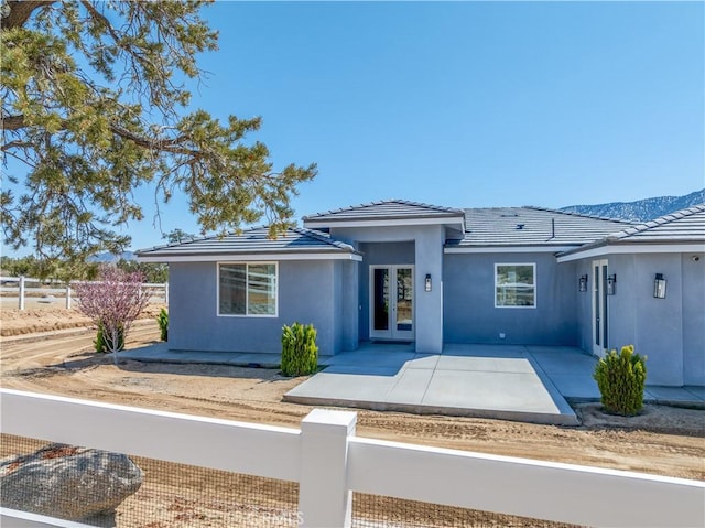 view of front of home with french doors, a fenced front yard, stucco siding, and a tile roof