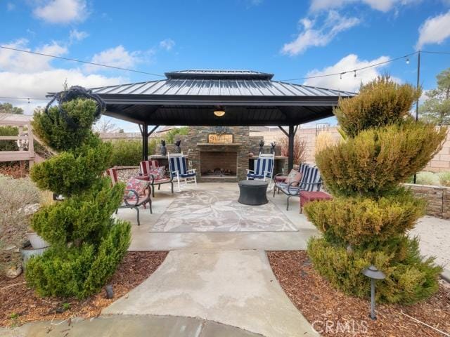 view of patio with a gazebo, an outdoor stone fireplace, and fence