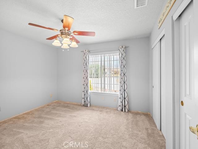 unfurnished bedroom featuring a ceiling fan, visible vents, a closet, a textured ceiling, and carpet flooring