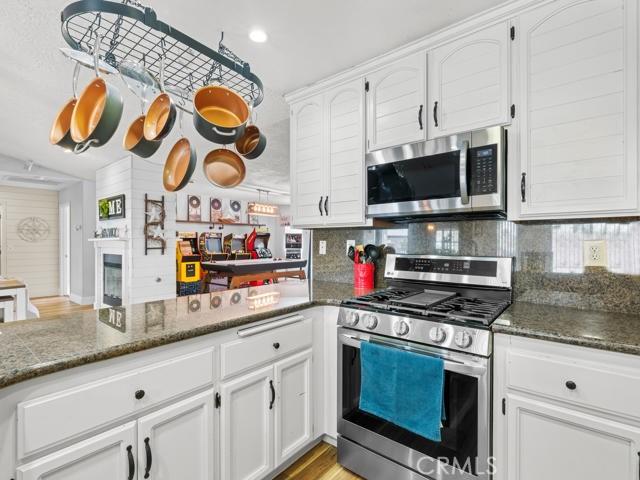 kitchen featuring decorative backsplash, appliances with stainless steel finishes, white cabinetry, and a peninsula