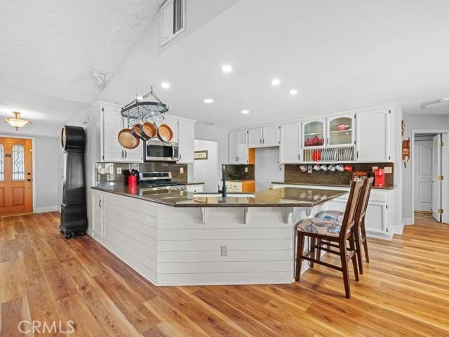 kitchen featuring dark countertops, visible vents, light wood-type flooring, a peninsula, and stainless steel appliances