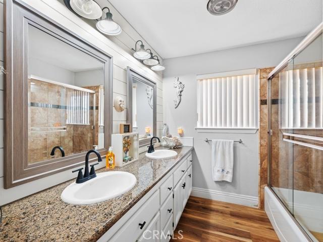 bathroom featuring double vanity, wood finished floors, baseboards, and a sink