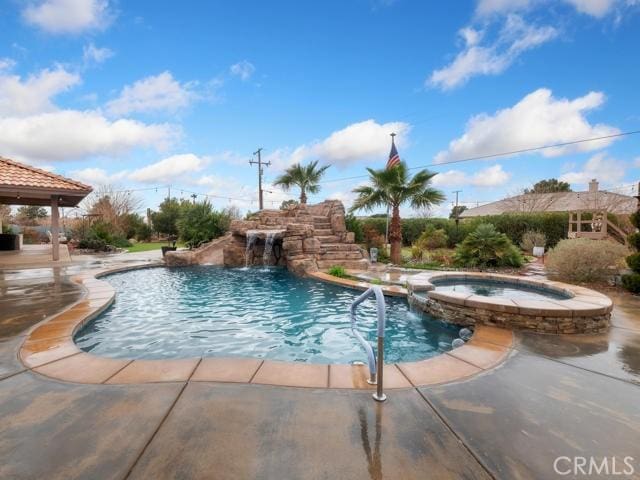 view of swimming pool featuring a pool with connected hot tub and a patio