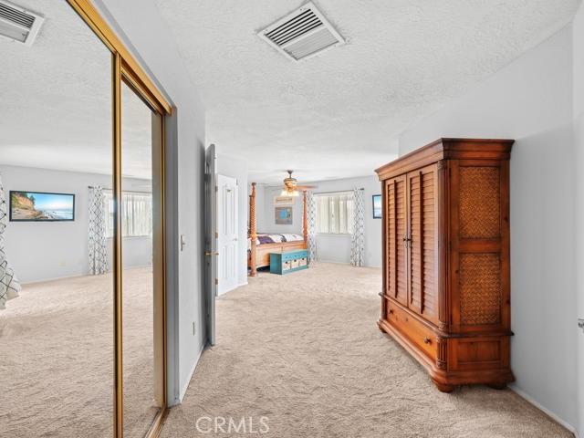 hallway featuring a textured ceiling, visible vents, and light carpet