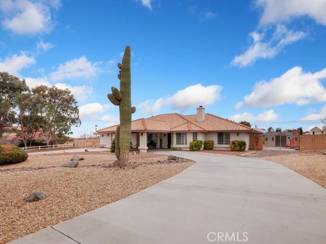 single story home with stucco siding, driveway, a tile roof, fence, and a chimney