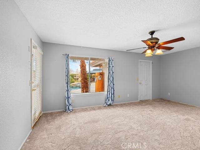 empty room featuring a textured ceiling, carpet, and a ceiling fan