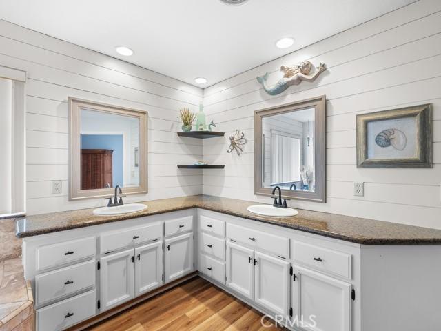 bathroom featuring double vanity, recessed lighting, wood finished floors, and a sink