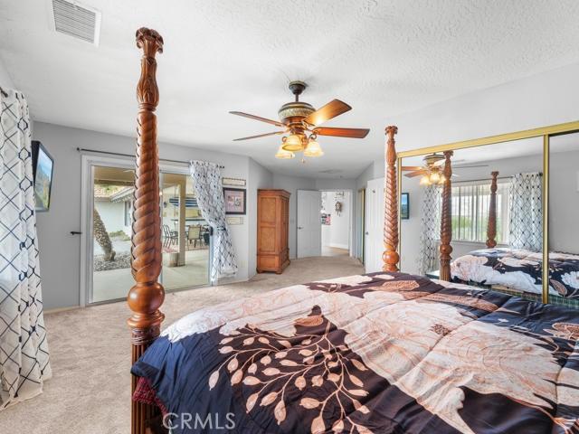 bedroom featuring visible vents, light carpet, a closet, a textured ceiling, and a ceiling fan