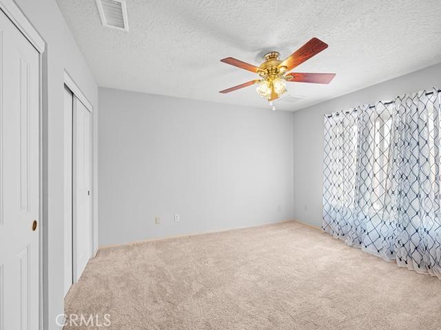 unfurnished bedroom featuring visible vents, a textured ceiling, a ceiling fan, and carpet floors