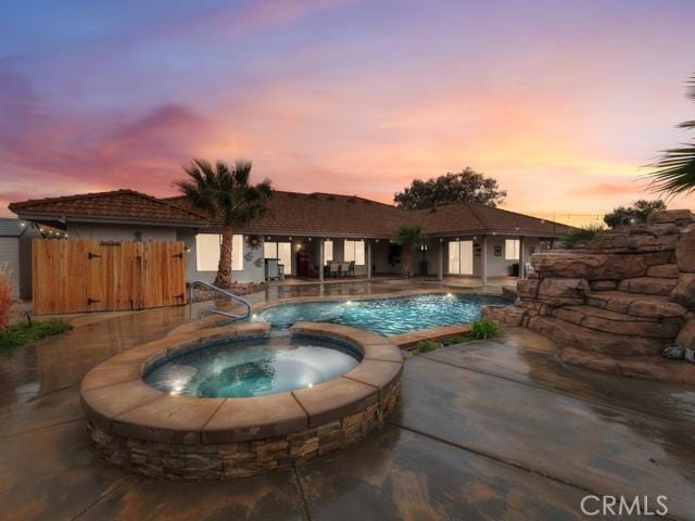 view of swimming pool featuring a patio area, a pool with connected hot tub, and fence