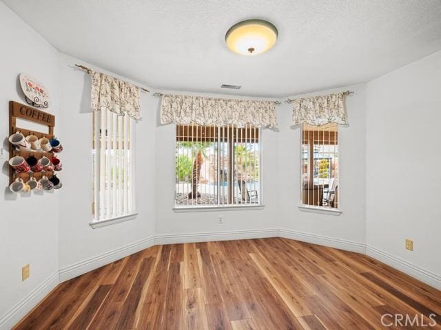 spare room with baseboards and wood finished floors