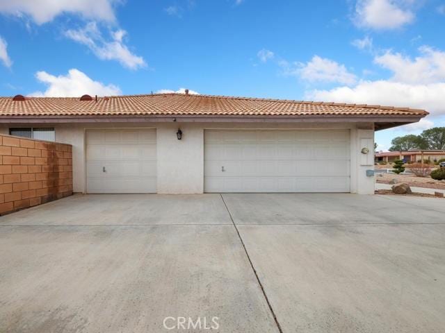 garage with concrete driveway and fence