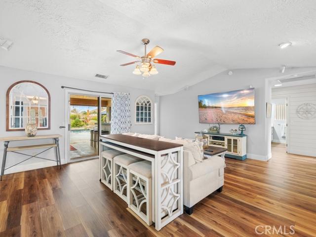 living room featuring visible vents, a textured ceiling, ceiling fan, and wood finished floors