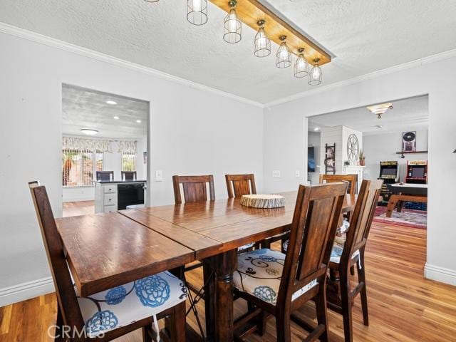 dining area with baseboards, a textured ceiling, crown molding, and light wood finished floors