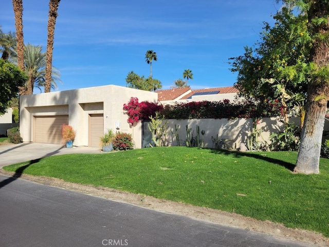 view of front of home featuring concrete driveway, an attached garage, a front lawn, and stucco siding