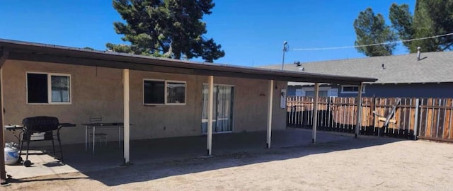 rear view of property with a patio, stucco siding, and fence