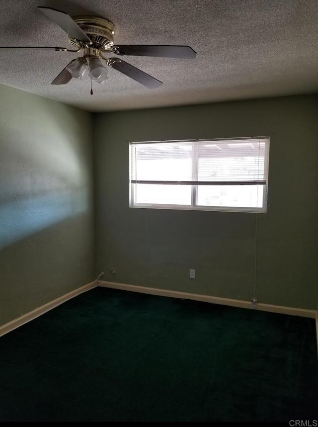 spare room with baseboards, a ceiling fan, dark colored carpet, and a textured ceiling