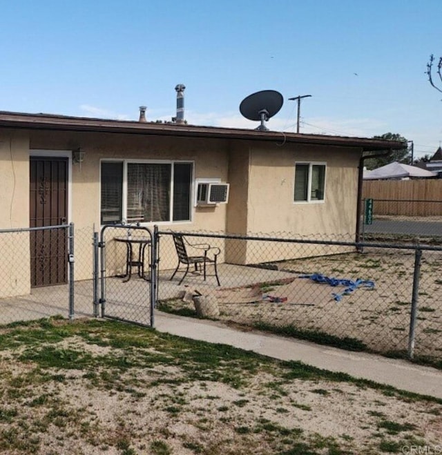 exterior space featuring an AC wall unit, fence, a gate, and stucco siding