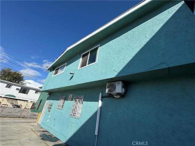 view of side of property with stucco siding, fence, and ac unit