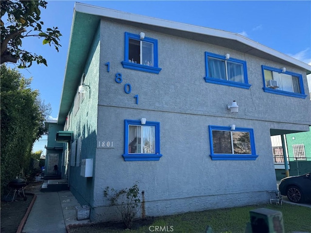 view of side of home with stucco siding and cooling unit