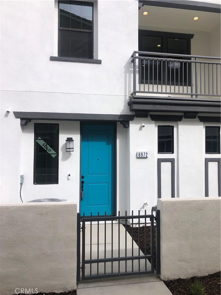 entrance to property featuring a balcony, a gate, fence, and stucco siding