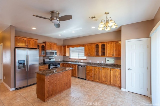 kitchen featuring visible vents, a kitchen island, stainless steel appliances, glass insert cabinets, and brown cabinets