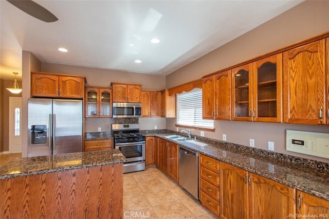 kitchen featuring a sink, appliances with stainless steel finishes, dark stone countertops, and brown cabinetry