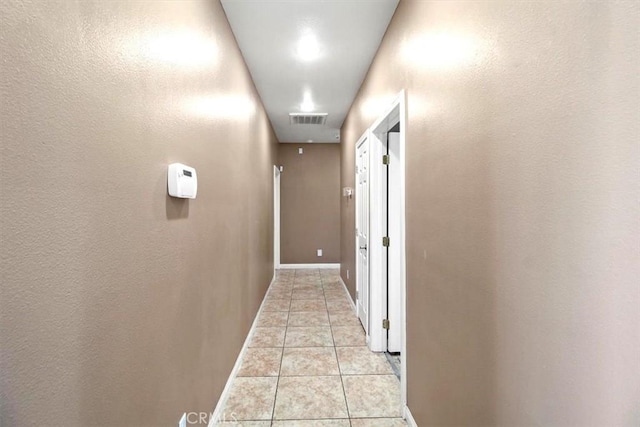 hall featuring light tile patterned flooring, baseboards, and visible vents