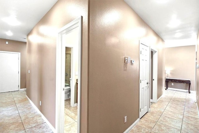 hallway with light tile patterned floors and baseboards