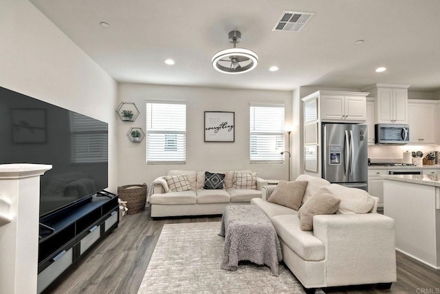 living room with recessed lighting, wood finished floors, and visible vents