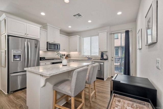 kitchen featuring white cabinets, appliances with stainless steel finishes, visible vents, and light wood-style floors