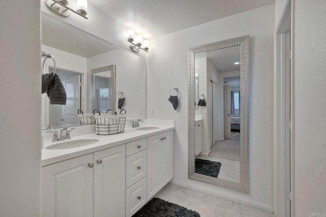 ensuite bathroom with double vanity, a sink, ensuite bathroom, and tile patterned flooring