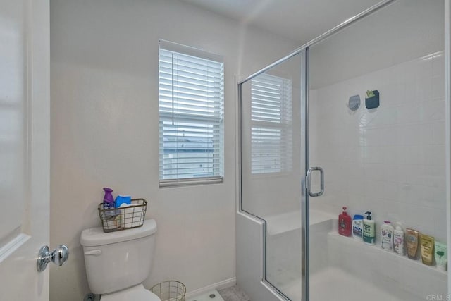 bathroom featuring baseboards, a stall shower, and toilet