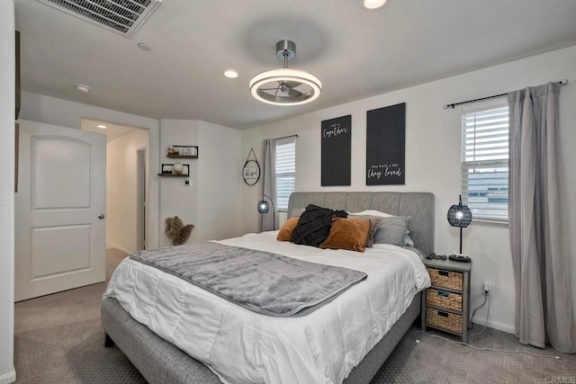 carpeted bedroom featuring recessed lighting, baseboards, visible vents, and multiple windows